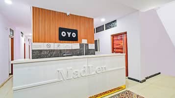 A reception desk with 'Madlen' branding, a 'NO SMOKING' sign, and a 'GUEST ID CARD IS MANDATORY' notice.