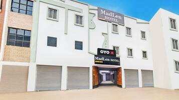 A hotel with a sign for MadLen Hotel and OYO, featuring a modern facade with multiple windows and a central entrance.