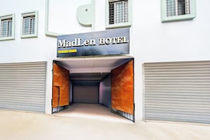 Entrada de un hotel con un cartel que dice 'MadLen Hotel' y 'Habitaciones Premium'.