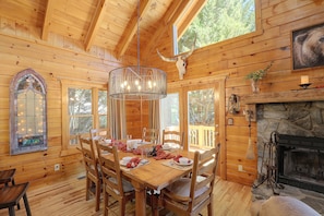 Um interior de madeira com uma mesa de jantar posta para quatro pessoas, rodeada por cadeiras.