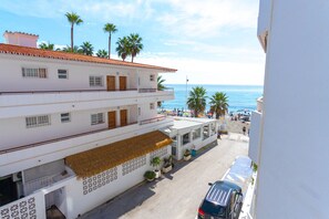 A multi-story building with a balcony overlooking a beach, a parked car, and palm trees. - Torresol Torrecilla 308 by Casasol (Nerja)
