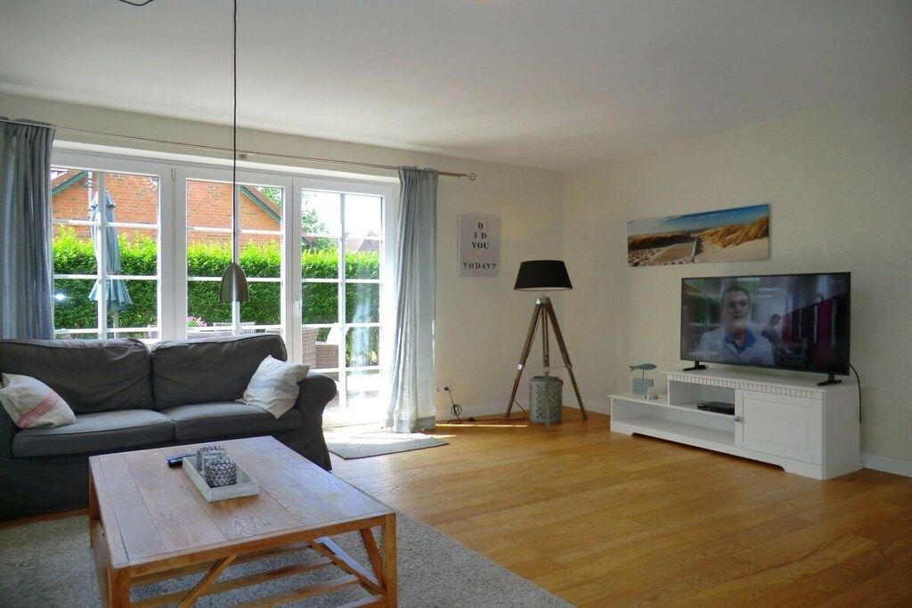 Een woonkamer met een bank, salontafel, televisie en een driepoot lamp.