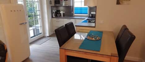 A compact kitchen with a dining table, chairs, and a refrigerator.