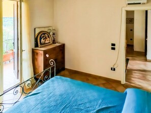 A bedroom with a bed, a dresser, a picture frame, and a door leading to another room. - Large Family Vacation Home (Villa San Nicola)