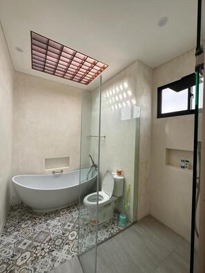 Un bagno moderno con una vasca da bagno indipendente, un water e un box doccia in vetro.