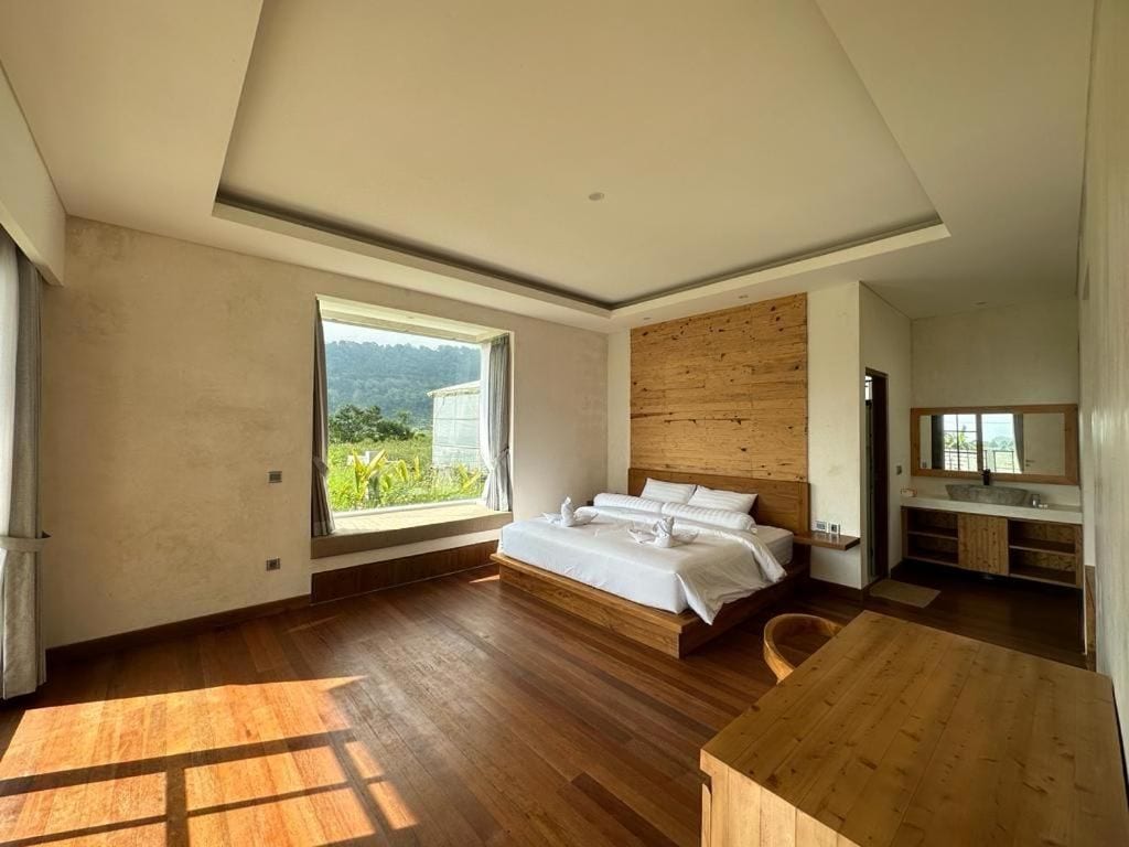 Camera da letto moderna con un letto di legno, un'ampia finestra e vista sul verde.