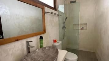 Une salle de bain avec un lavabo en marbre, des toilettes et une douche à parois de verre.