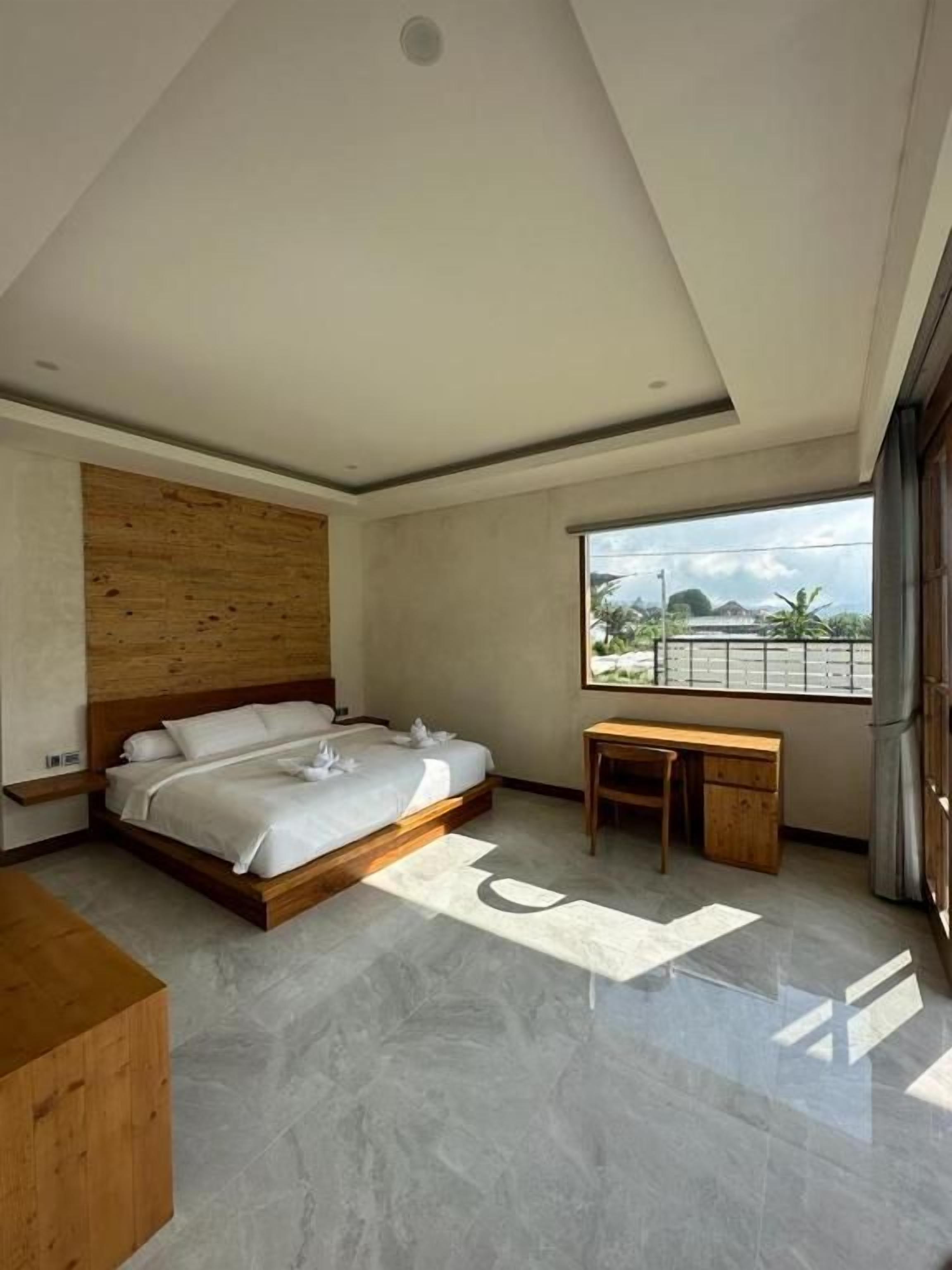 Een moderne slaapkamer met een bed, een bureau en uitzicht op het landschap.