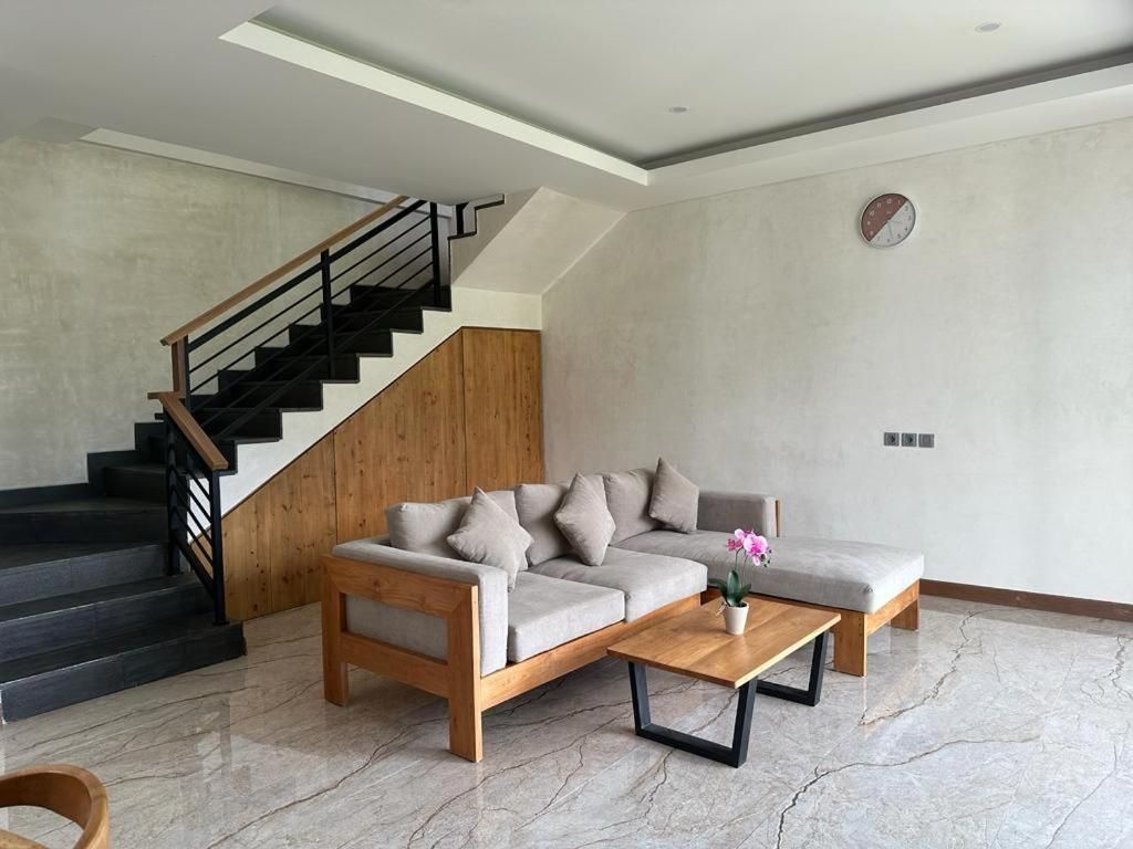 Een moderne woonkamer met een bank, salontafel en een houten trap.