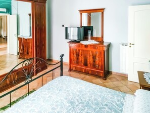 Ein Schlafzimmer mit einem Bett, einem Holzkleiderschrank mit Spiegel und einem Schrank.