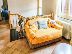 Ein Bett mit gemustertem Überwurf, einem Holz-Kopfteil und einem Fenster mit Jalousien.