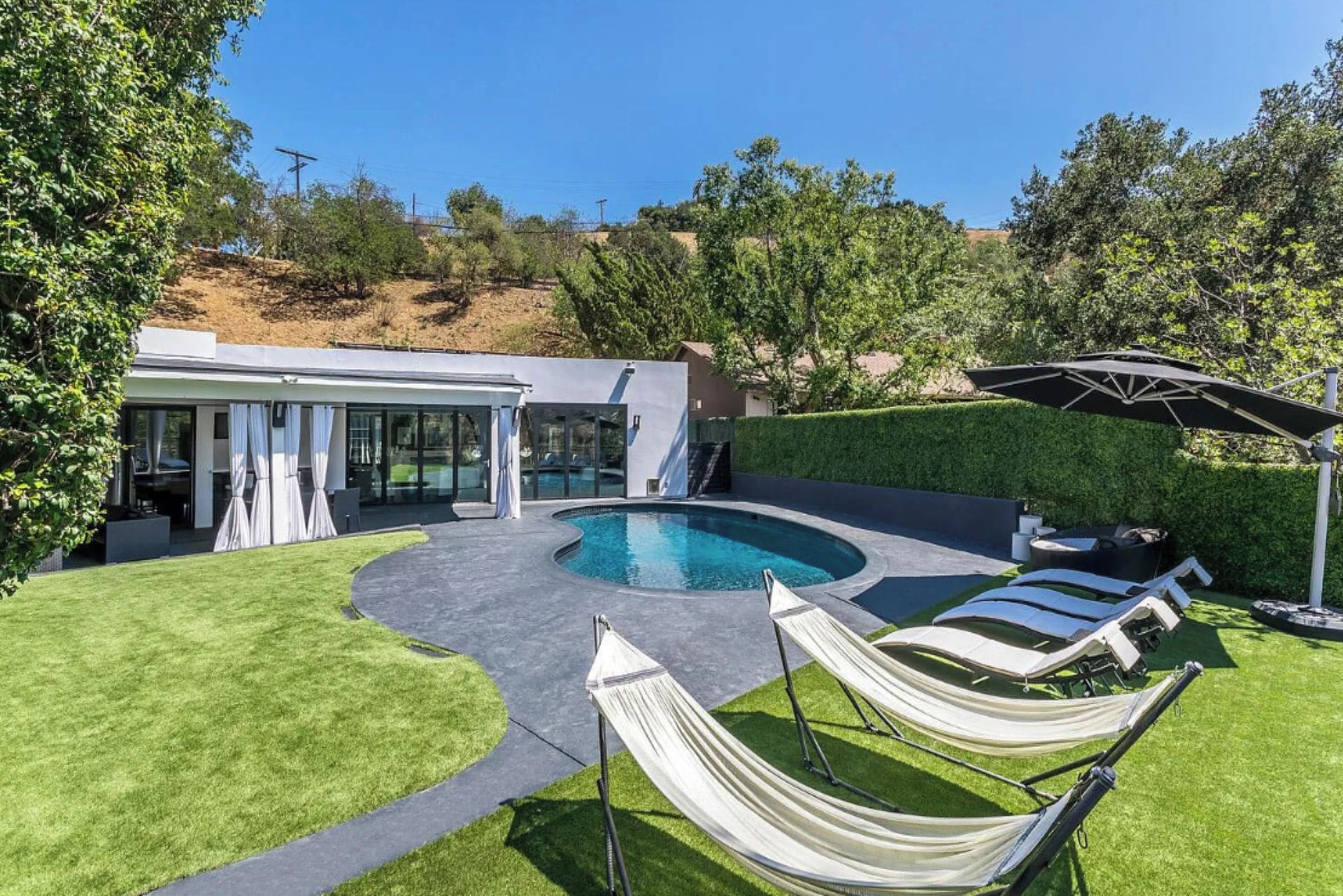 A modern house with a swimming pool, outdoor seating, and a covered patio area.