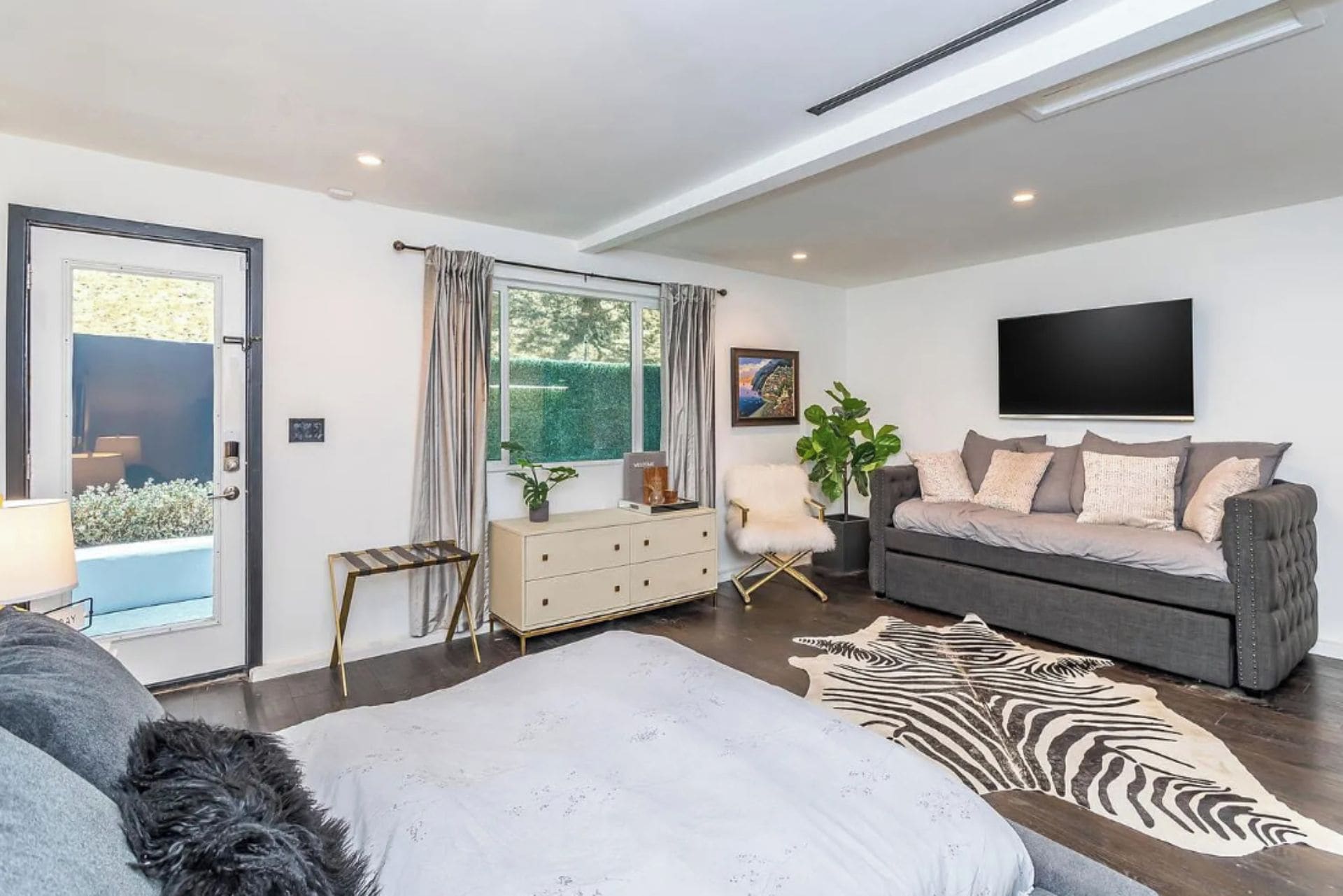 A modern living room with a sofa, a zebra rug, and a television.