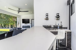 A modern kitchen with a long island, built-in appliances, and a flat-screen TV. - Oakfield Rise (Sherman Oaks)