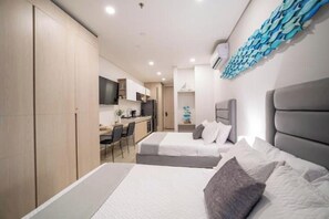 A modern bedroom with two beds, a kitchenette, and a dining area. - Luxury Oceanfront Apartment in Belo Horizonte (Santa Marta)