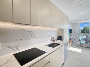 A modern kitchen with a built-in stove, a sink, and a window overlooking a scenic view. - Bright 1-Bed Apartment Near Batemans Bay (Batemans Bay)