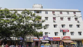 Un edificio de varios pisos con diversos comercios en la planta baja, incluyendo una clínica y una tienda móvil.