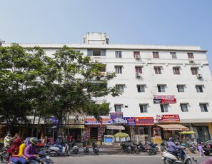 A multi-story building with various commercial establishments on the ground floor, including a clinic and a mobile shop.