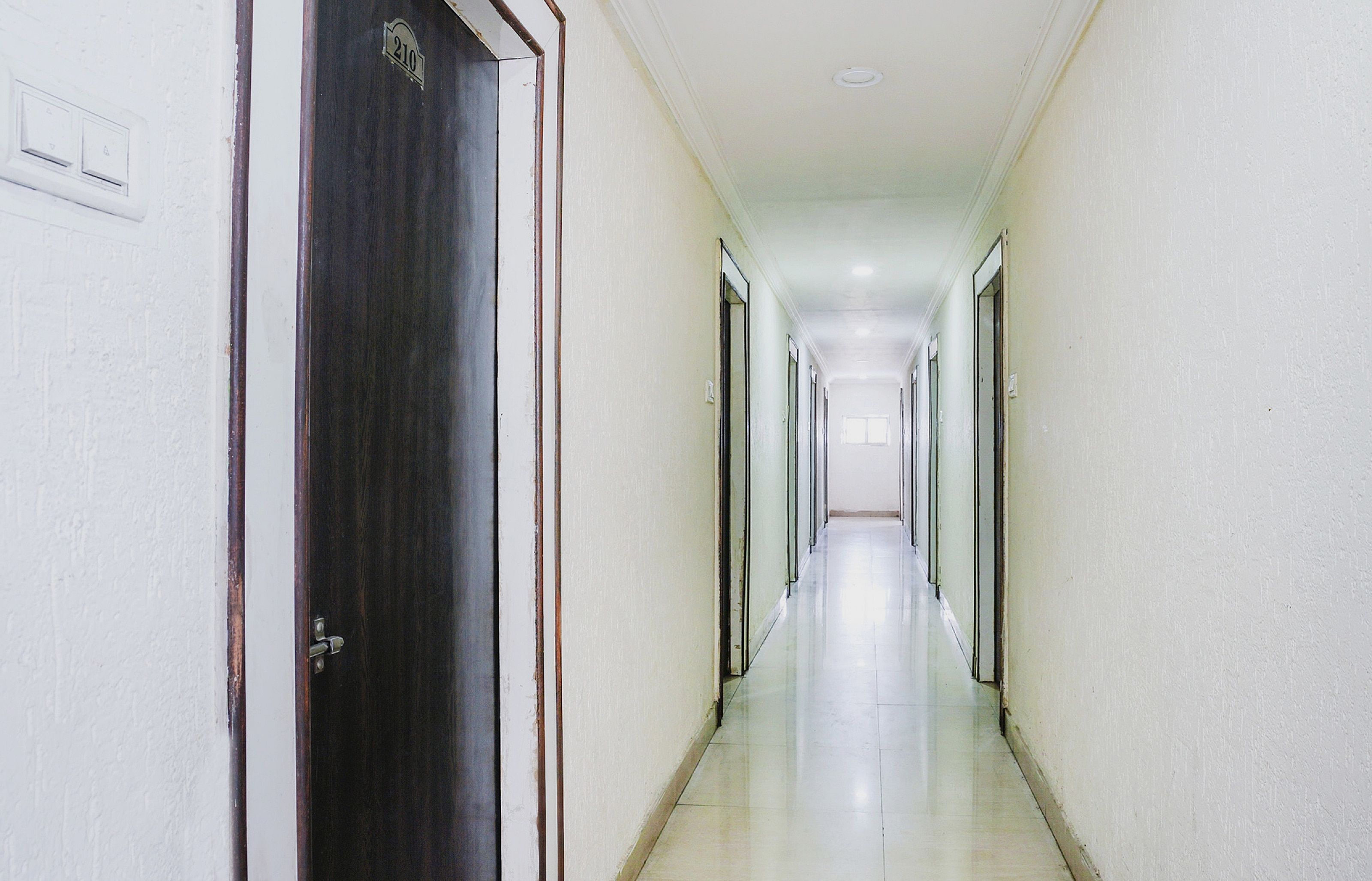 Un pasillo largo y estrecho con puertas a ambos lados, que conduce a habitaciones individuales.