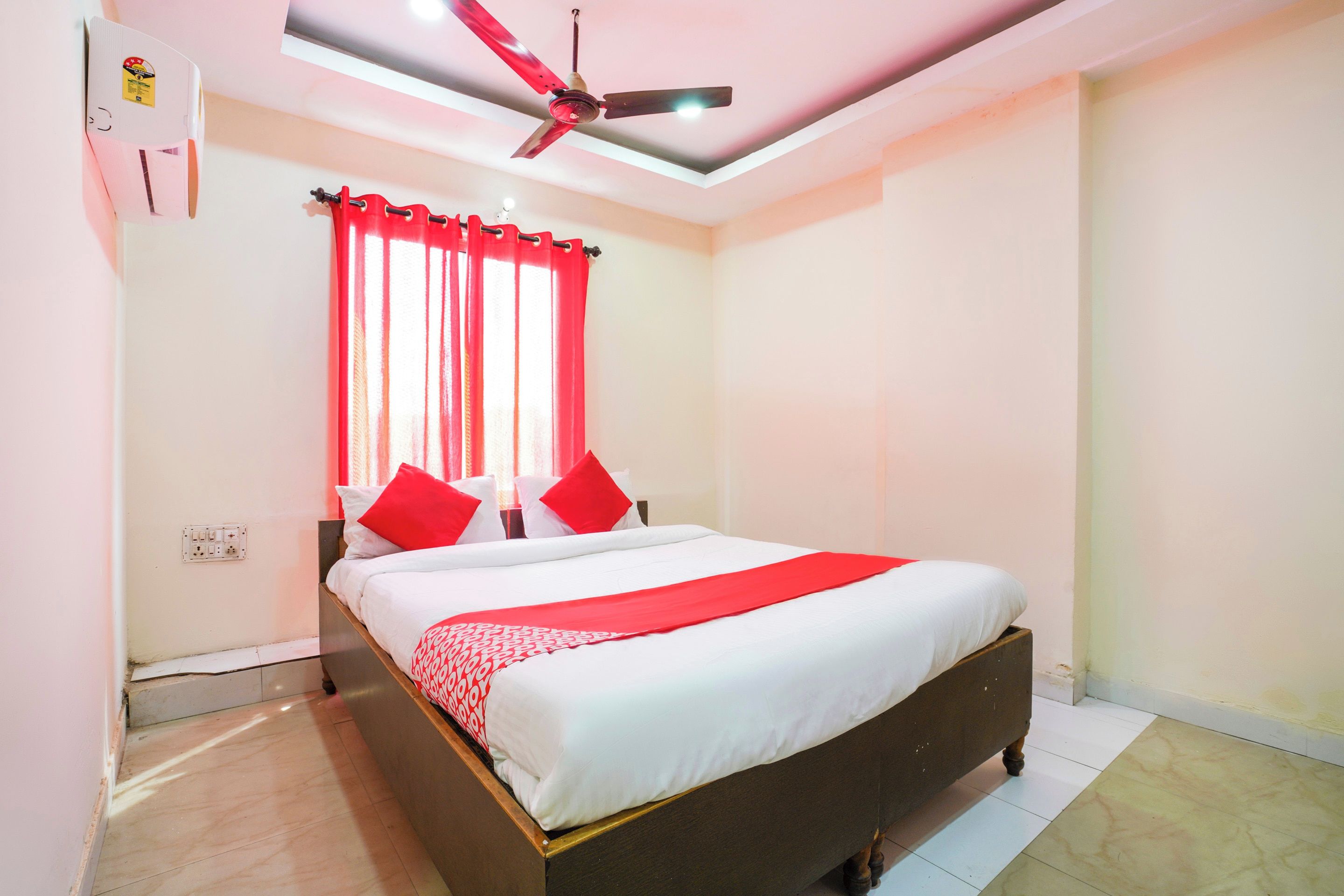 Un dormitorio con cama, cortinas rojas, ventilador de techo e iluminación.