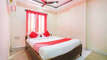Un dormitorio con cama, cortinas rojas, ventilador de techo e iluminación.
