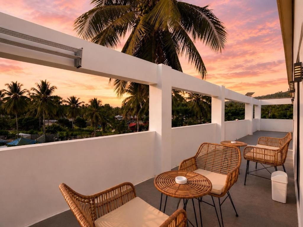 A balcony with wicker furniture and a view of palm trees.