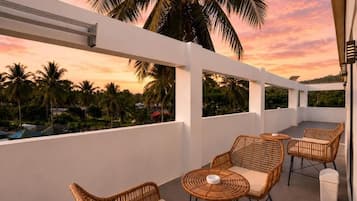 A balcony with wicker furniture and a view of palm trees.