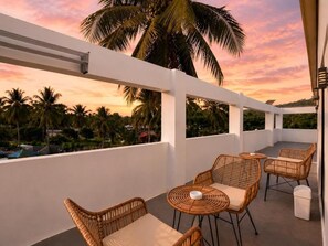 A balcony with wicker furniture and a view of palm trees.