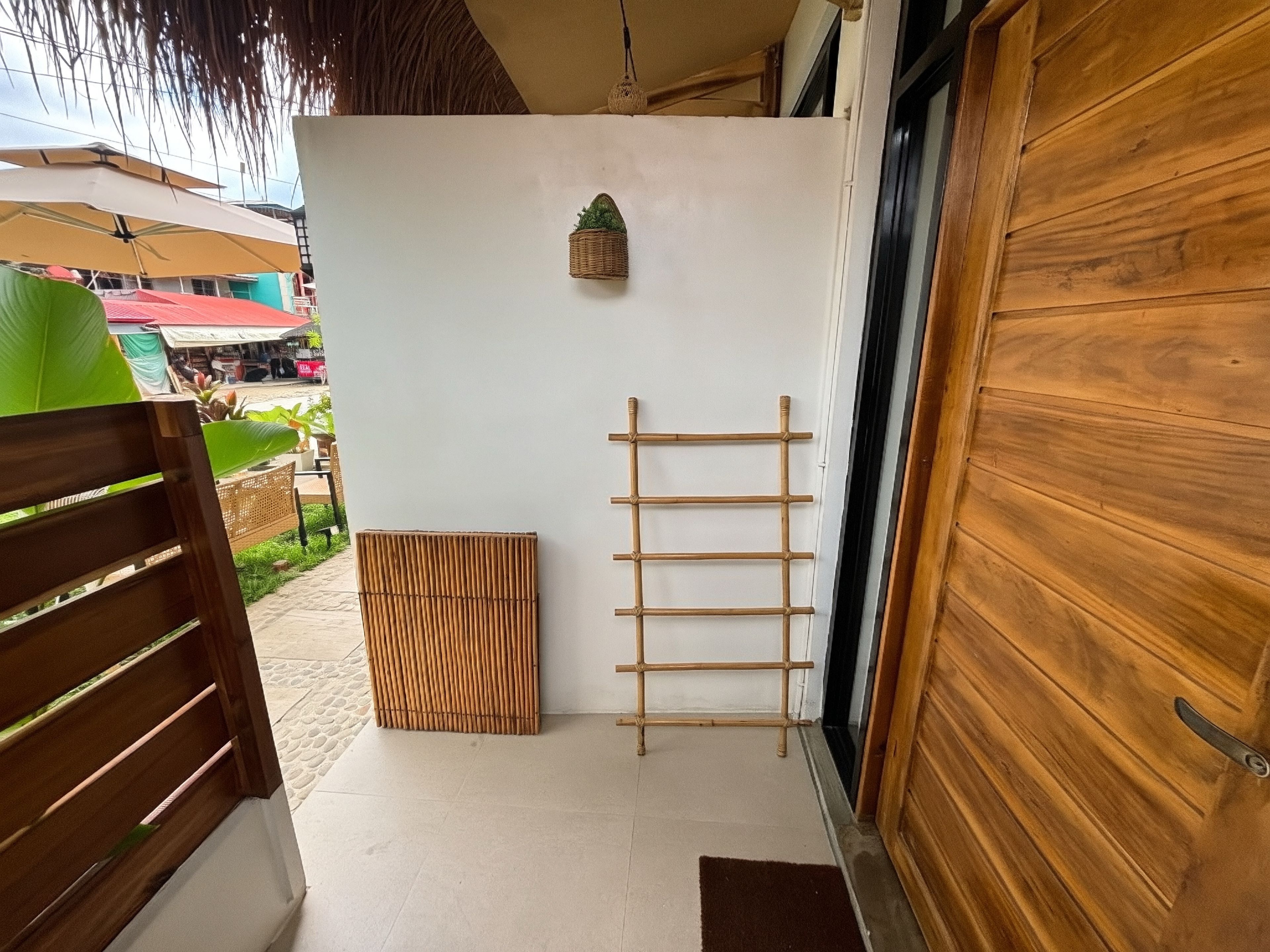 A wooden door, a bamboo screen, and a white wall with a small hanging basket.