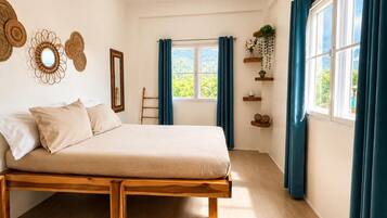 A bedroom with a wooden bed, a window with curtains, and wall decorations.