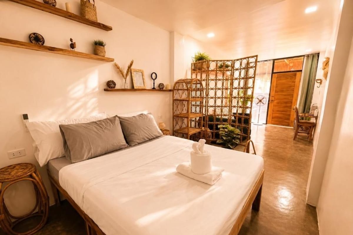 A hotel room with a bed, bedside table, and a decorative wall shelf.
