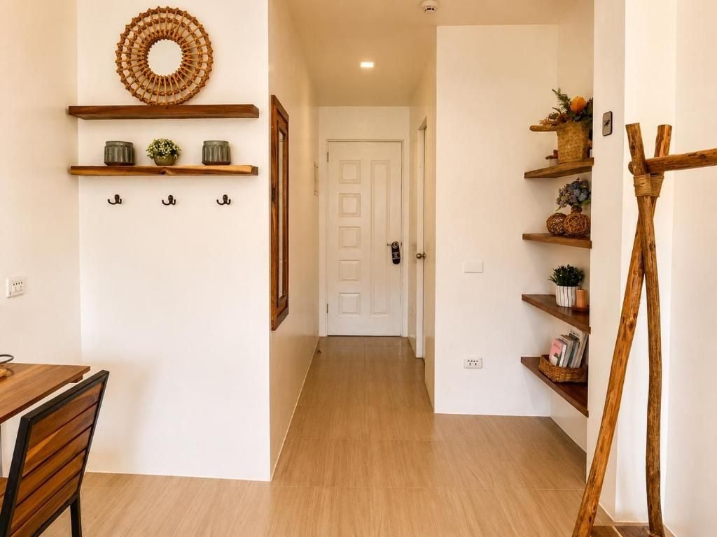 Un pasillo con piso de madera, una puerta blanca al final y estantes con adornos.