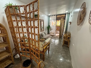 A room with a rattan partition, a sofa, a wooden chair, and a small table.