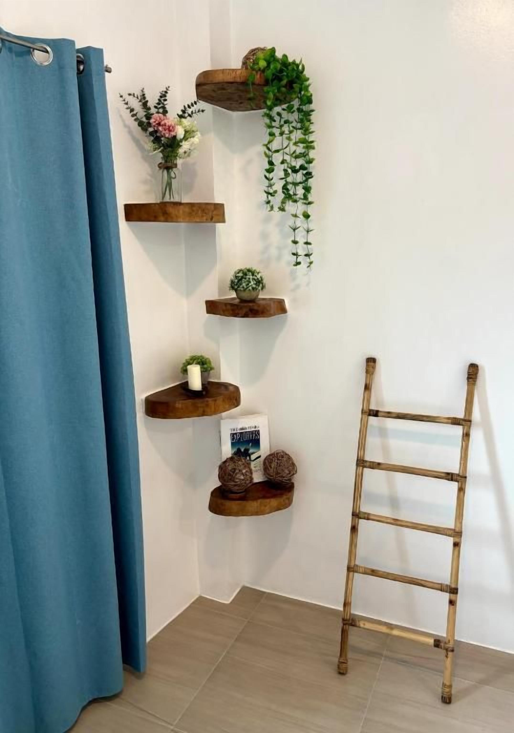 Een badkamer met een blauw douchegordijn, houten planken met planten, en een bamboe trapje.
