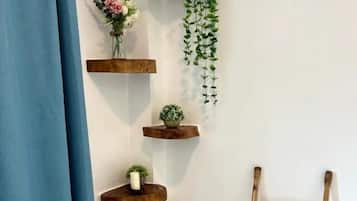 Een badkamer met een blauw douchegordijn, houten planken met planten, en een bamboe trapje.