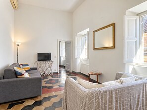 A living room with a sofa, a television, and a lamp. There is a hallway leading to another room. - Appartamento Chiavari by Geco Vacation Rentals (Rome)