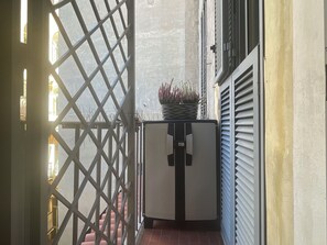 A narrow corridor with a metal gate, a small table with a potted plant, and a door with a handle. - Appartamento Chiavari by Geco Vacation Rentals (Rome)