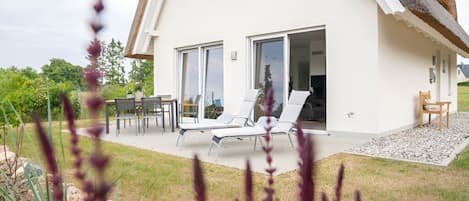 Uma casa moderna com um pátio, área de estar externa e vista para a paisagem ao redor.