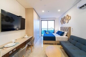 Ein modernes Schlafzimmer mit Bett, Sofa, Fernseher und Schreibtisch.
