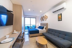 A modern hotel room with a bed, sofa, dining table, and a TV. - Luxury Apartment with Ocean View in Bello Horizonte (Santa Marta)