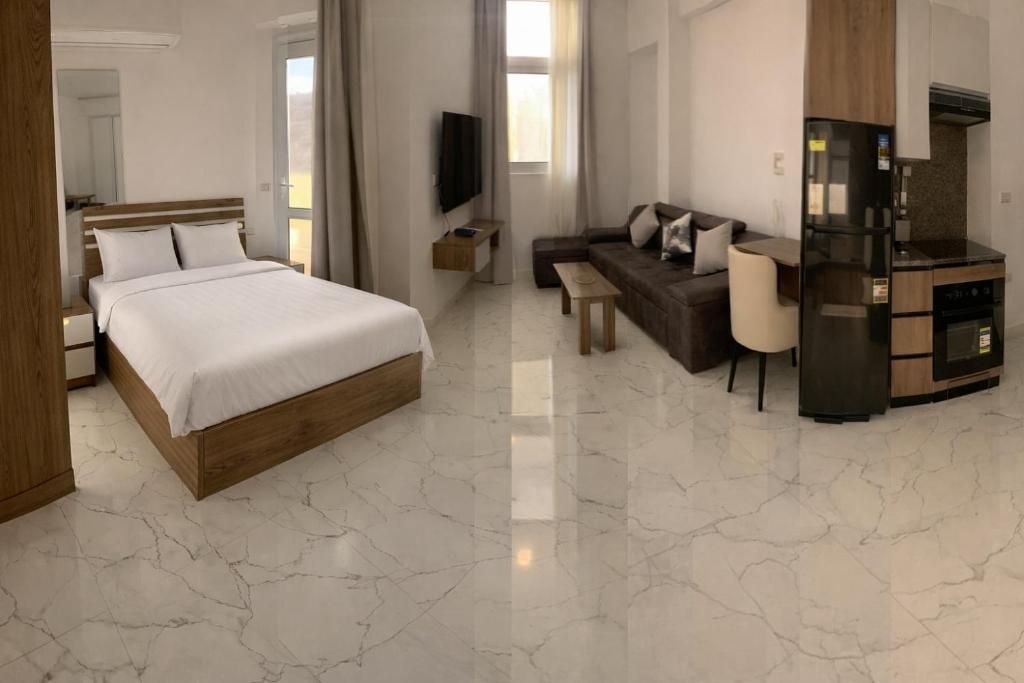 Een hotelkamer met een bed, een bank, een televisie, een tafeltje en een kitchenette.