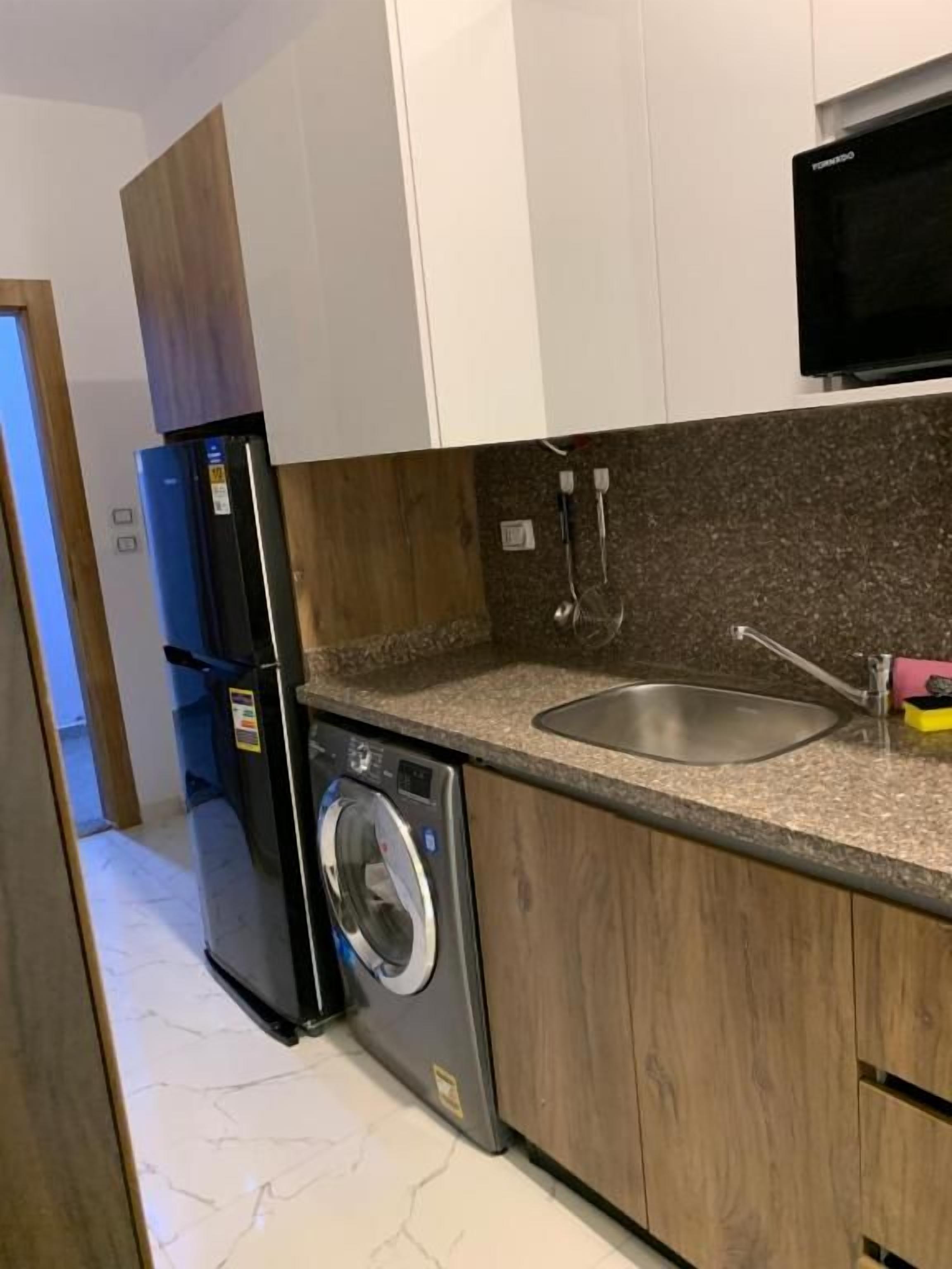 Een kleine keuken met een wasmachine, een spoelbak en een magnetron.