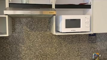 Eine Küche mit einer Mikrowelle, einer schwarzen Arbeitsplatte und einem Edelstahl-Spülbecken.