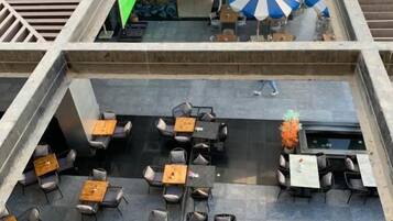 Een terras met tafels en stoelen, een overdeeld gedeelte met parasols en uitzicht op de straat.