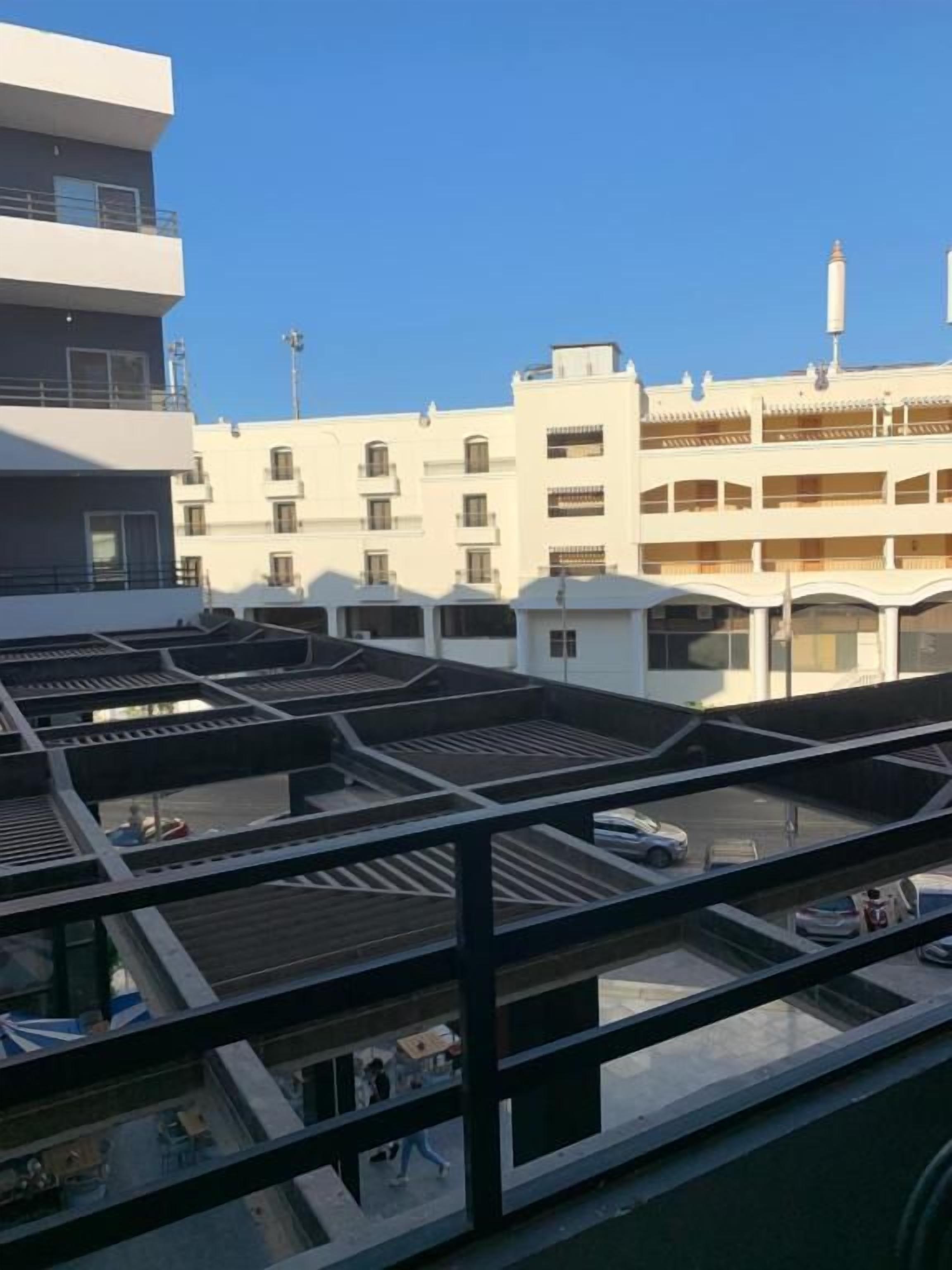 Een meerlaags gebouw met balkons en een parkeerplaats.