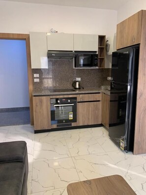 Een kleine keuken met een magnetron, oven en koelkast.