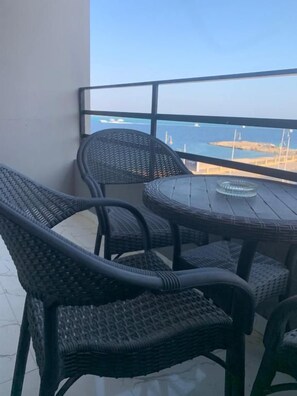 Een balkon met rieten meubilair en uitzicht op zee.