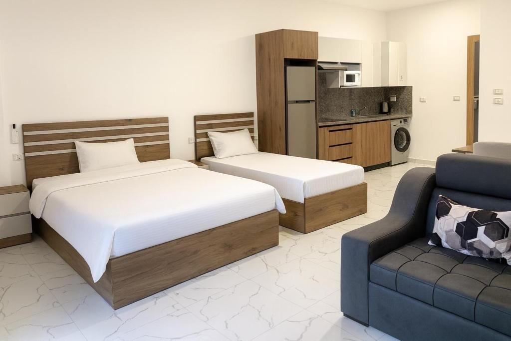 Ein Hotelzimmer mit zwei Betten, einer Couch, einer Waschmaschine und einer Küchenzeile.