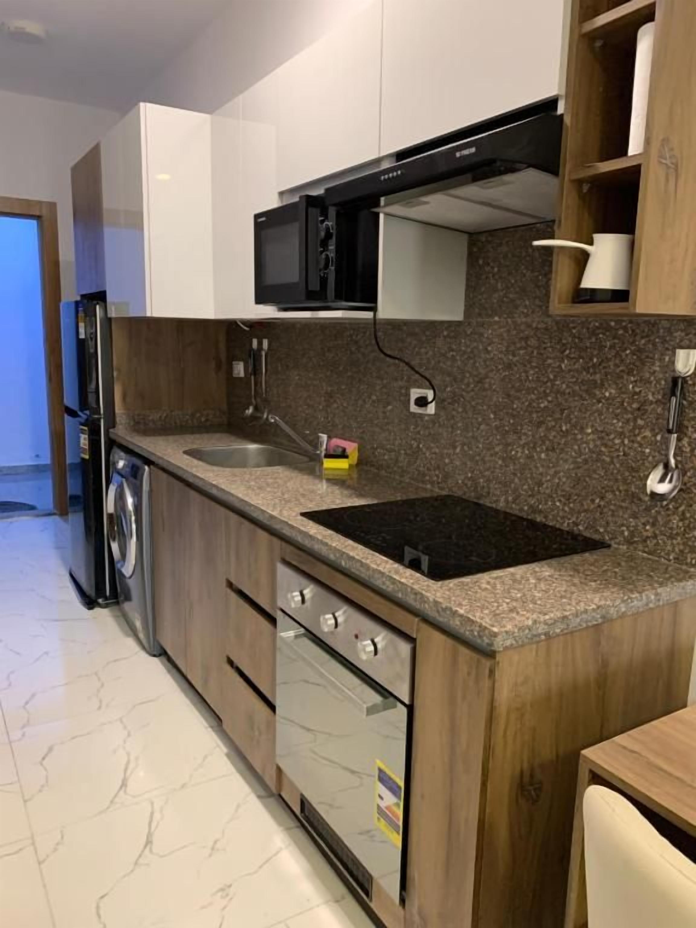 A kitchen with a built-in microwave, oven, and sink.