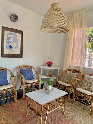 A room with wicker furniture, a hanging light fixture, a framed artwork, and a potted plant. - La Case de L'Artiste- 2 bedroom appartment in Bain Boeuf, 5 mins from the beach. (Cap Malheureux)